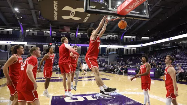 Chance Gladden hits a slam dunk with both hands with his teammates watching on during pregame warmup
