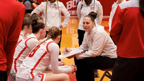 Photo of BU women's basketball head coach Melissa Graves instructing player on the BU bench at Case Gym.