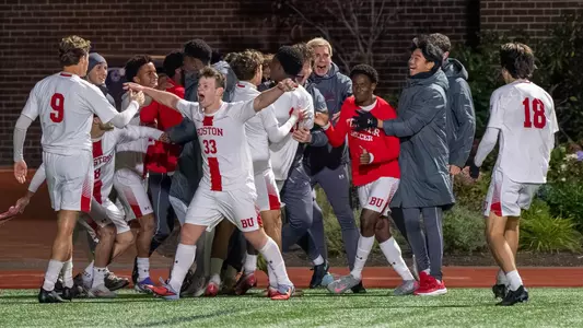Men's Soccer team celebrates a goal scored against Holy Cross in a group gathering near the sideline