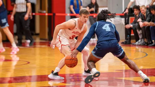 Ben Roy crouches into a defensive position with a Maine player bringing the ball up the court.