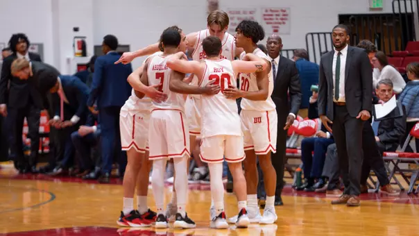 men's basketball starters huddle up in a circle