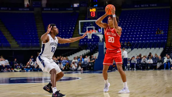 Michael McNair holds the ball above his shoulders looking to pass it with a Penn State defender close by