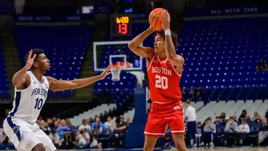 Michael McNair holds the ball above his shoulders looking to pass it with a Penn State defender close by