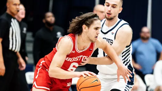 Sam Hughes drives the ball toward the hoop with a UNH defender guarding him