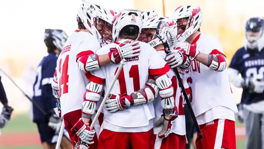 Men's lacrosse players celebrate a goal against Monmouth