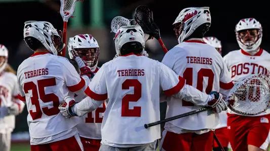 Men's lacrosse players huddle after a win