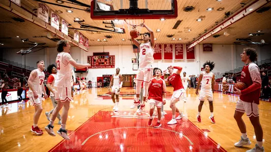 The team gathers around the hoop as Ben Palacios hits a slam dunk in a pregame routine.