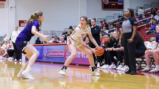 Photo of women's basketball freshman Inez Gallegos sizing up a Holy Cross defender at Case Gym.