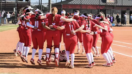 BU softball players are jumping while in a huddle