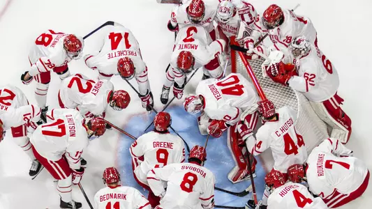 BU men's hockey players huddle at their net before a game