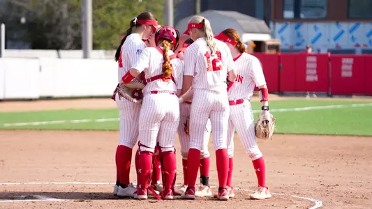 The infielders and pitcher huddle in the circle at home