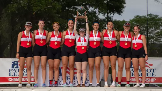 Women's rowing boat of the year poses on stage with trophy