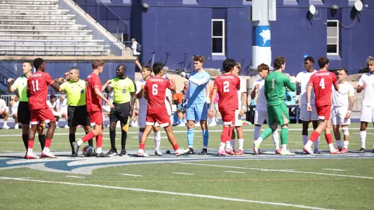 Men's soccer starters exchange fist bumps with UNH after the starting lineups are announced