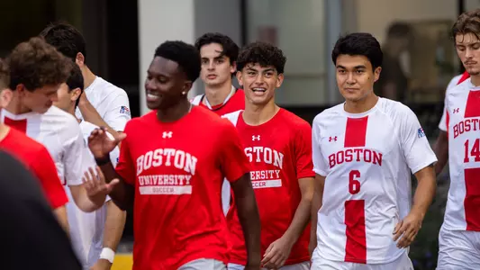 Men's Soccer players walk out the Case Center in uniform toward the bench at Nickerson Field.