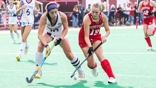 A BU field hockey player competes against a Holy Cross field hockey player