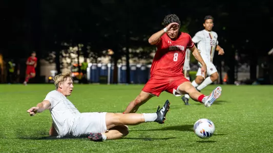 Sebastian Otero charges after the soccer ball, as a Boston College player slides in attempt to kick the ball away