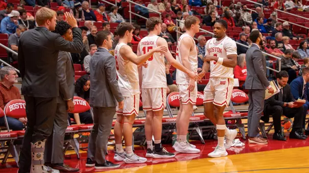 Malcolm Chimezie is greeted by teammates as he returns to the bench during a substitution.