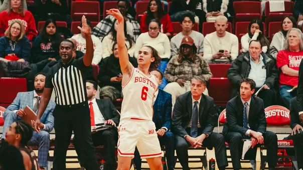 Sam Hughes attempts a 3-pointer in front of his bench.