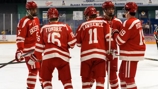 Men's ice hockey players huddle before a faceoff