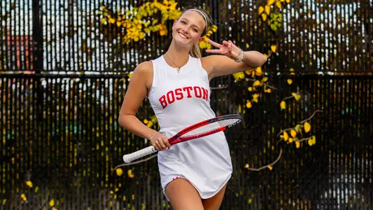Blanka DeMicheli smiles and shows a peace sign to the camera while playing tennis