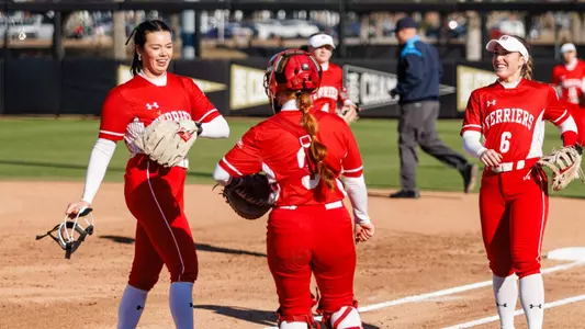 Kasey Ricard is greeted by Megan Coyle and Livia Christopher after finishing an inning with an important out.