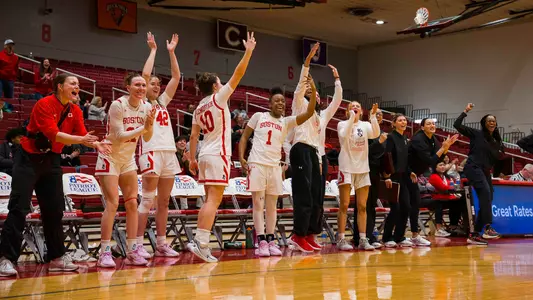 Photo of the BU Women's Basketball team bench celebrating at Case Gym.