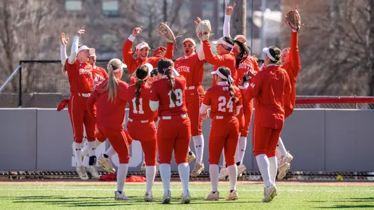 BU softball players jump up in the air as part of a huddle routine