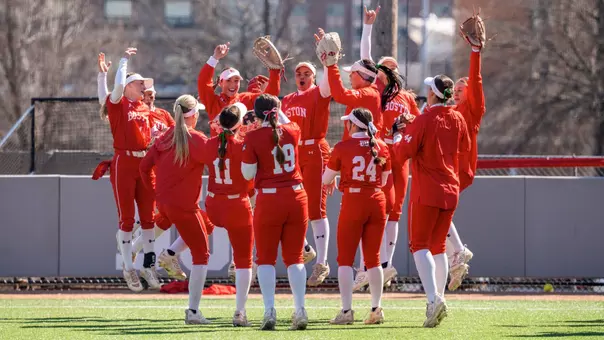 BU softball players jump up in the air as part of a huddle routine