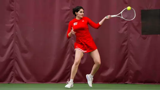 Rhea Rai hits a forehand on an indoor tennis court