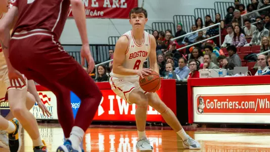 Peter Carr holds the basketball near midcourt with a Colgate defender in front of him