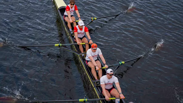 Photo of the BU Men's Rowing Varsity 8 racing on the Charles River.