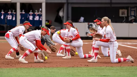BU softball infielders practice short grounders on the dirt during a pregame routine
