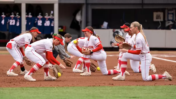 BU softball infielders practice short grounders on the dirt during a pregame routine
