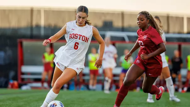 Photo of BU women's soccer senior Samantha Aronson dribbling the ball against a Harvard marker.
