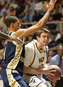 West Virginia forward Mike Gansey (20) looks to pass under the arms of George Washington forward Omar Williams (1).