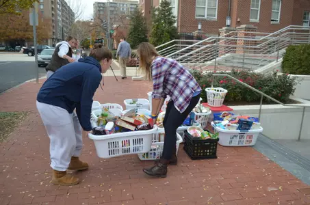Terasa Vassallo and Allie Rash help transport laundry baskets of Thanksgiving food from GW's Colonials Club to the delivery van.