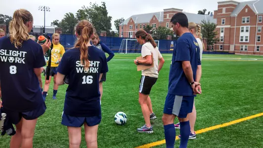Second-year Head Coach Sarah Barnes talks with the women's soccer team following Wednesday morning's practice session.