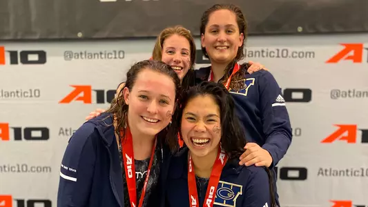 GW swimmers Andrea Ho, Meghan Burton, Stine Omdahl Petersen and Rebecca Smolcic pose with their gold medals