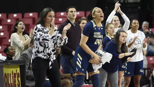 Women's basketball team celebrates from the bench.