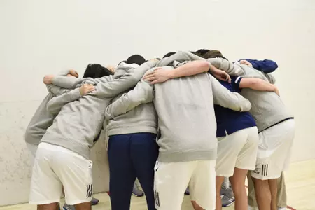 GW men's squash team in huddle.