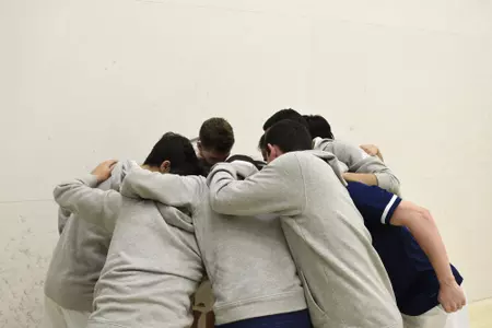 GW men's squash team in huddle.
