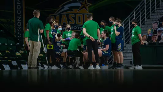 Women's basketball huddles during a timeout.