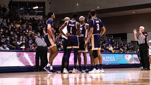 Men's basketball huddles on the court