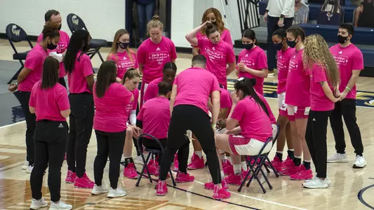 Women's basketball huddles during a timeout.