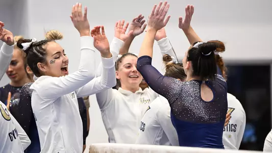 Hannah Munnelly and Anneliese Silverman high five after beam routine