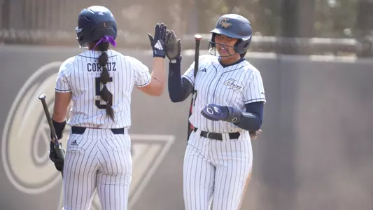 Emi Todoroki and Ashley Corpuz high fiving at the GW Softball Field