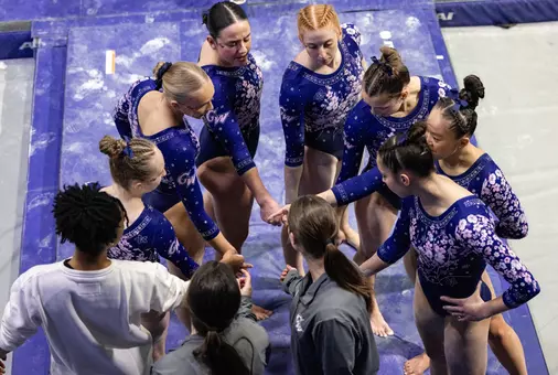 Gymnastics beam team huddles at Temple