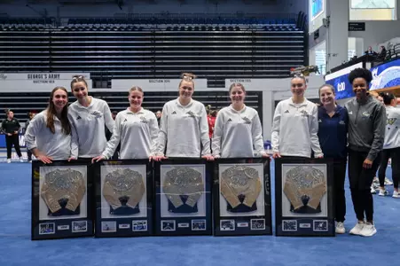 Seniors and GYM coaches pose together on senior night