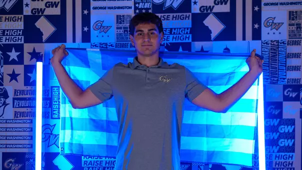 Konstantinos Kapragkos holding the Greek flag in front of a GW back drop