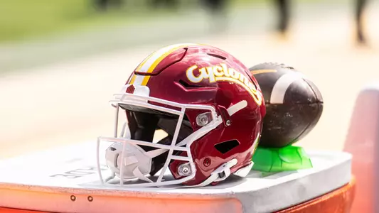 Iowa State cardinal helmet next to football.